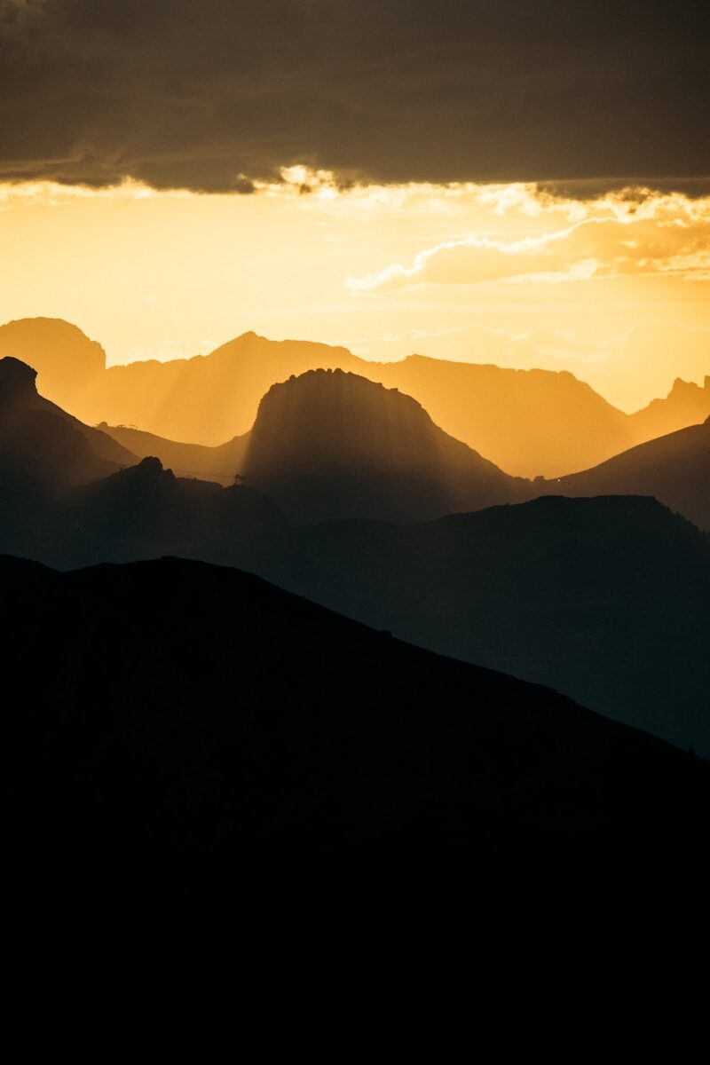 Silhouetted mountain ranges at golden hour sunset.